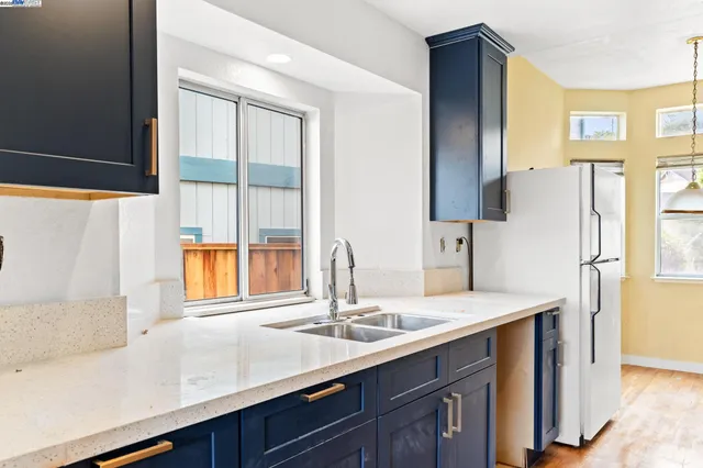 a kitchen with a sink a refrigerator and a large window