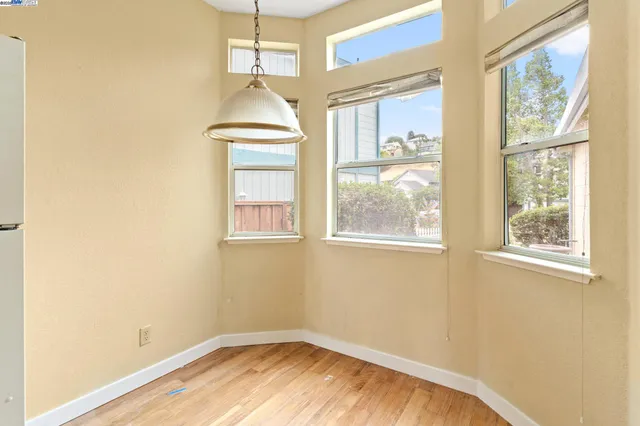 a view of empty room with wooden floor and fan