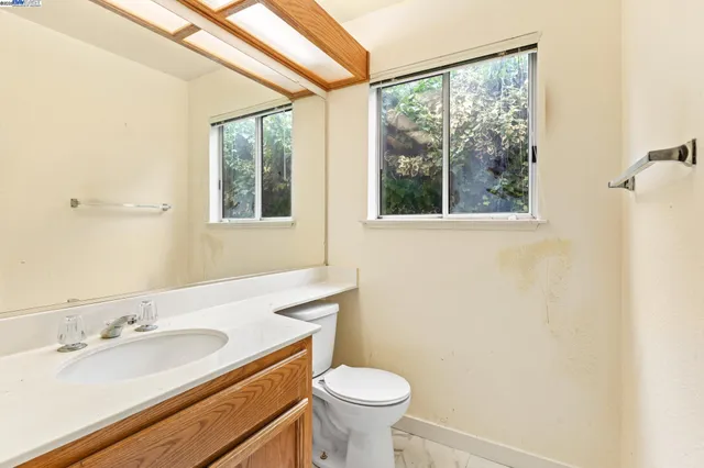 a bathroom with a granite countertop sink toilet and mirror