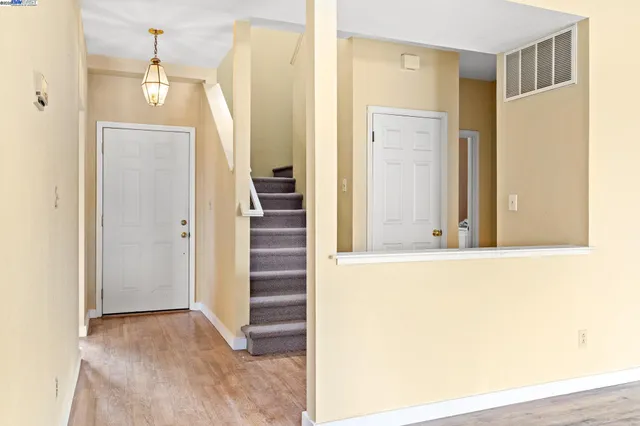 a view of a hallway to a bedroom with wooden floor and windows