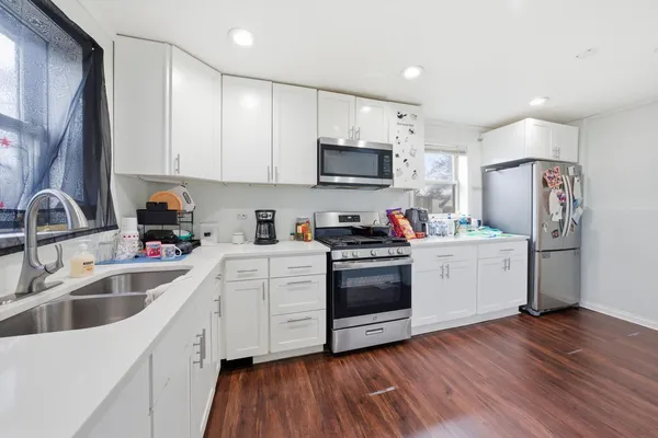 a kitchen with stainless steel appliances white cabinets a sink a stove a refrigerator and microwave