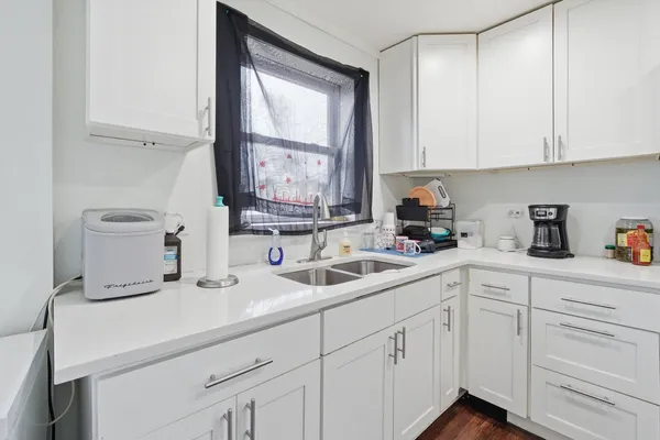 a kitchen with white cabinets and sink
