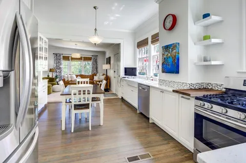 a kitchen with stainless steel appliances granite countertop a stove top oven a refrigerator and a dining table view