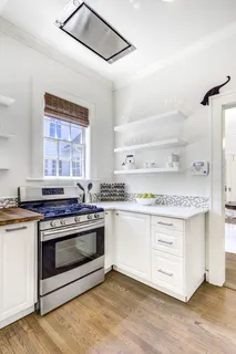 a kitchen with stainless steel appliances granite countertop a stove and white cabinets