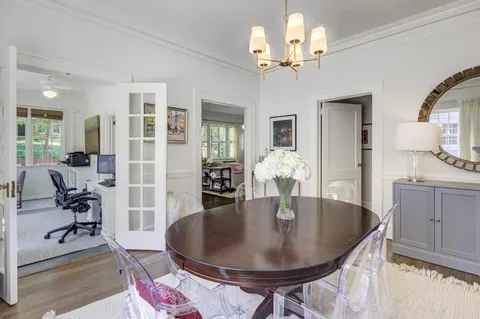 a dining room with wooden floor a chandelier a wooden table and chairs