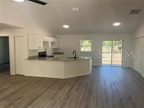 a large white kitchen with wooden floors and white walls