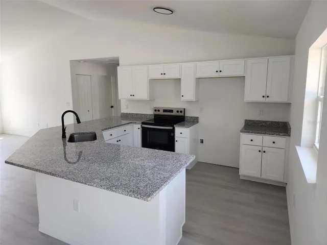 a kitchen with granite countertop a sink stove and refrigerator