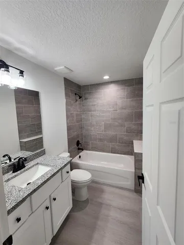 a bathroom with a granite countertop toilet a sink and bathtub