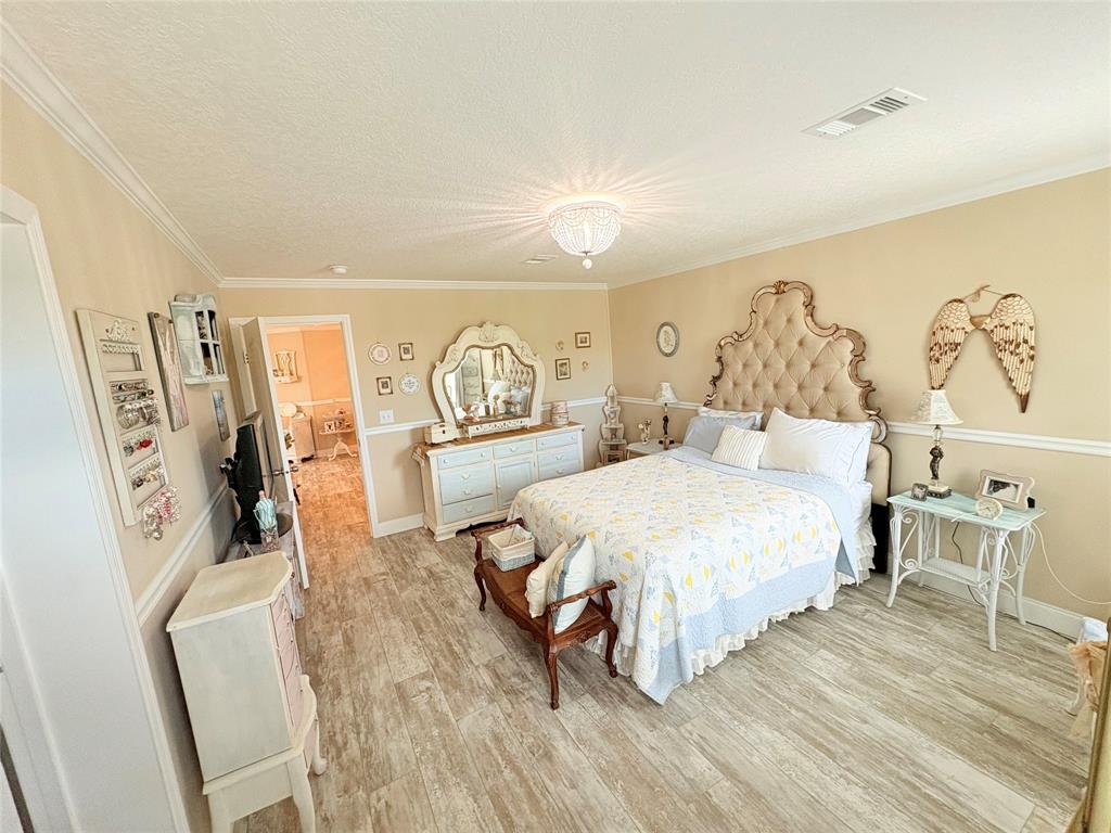 4331 Southwest 10th Way Okeechobee, FL 34974 - Photo 14 of 49 a spacious bedroom with a bed a table and painting on the wall