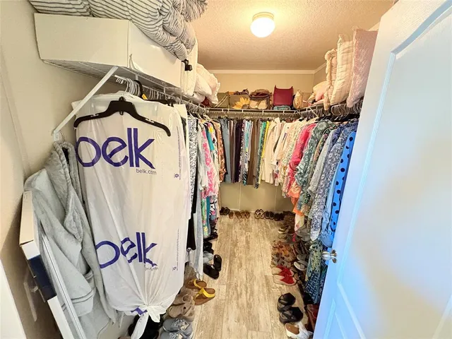 a view of walk in closet with clothes and shoes