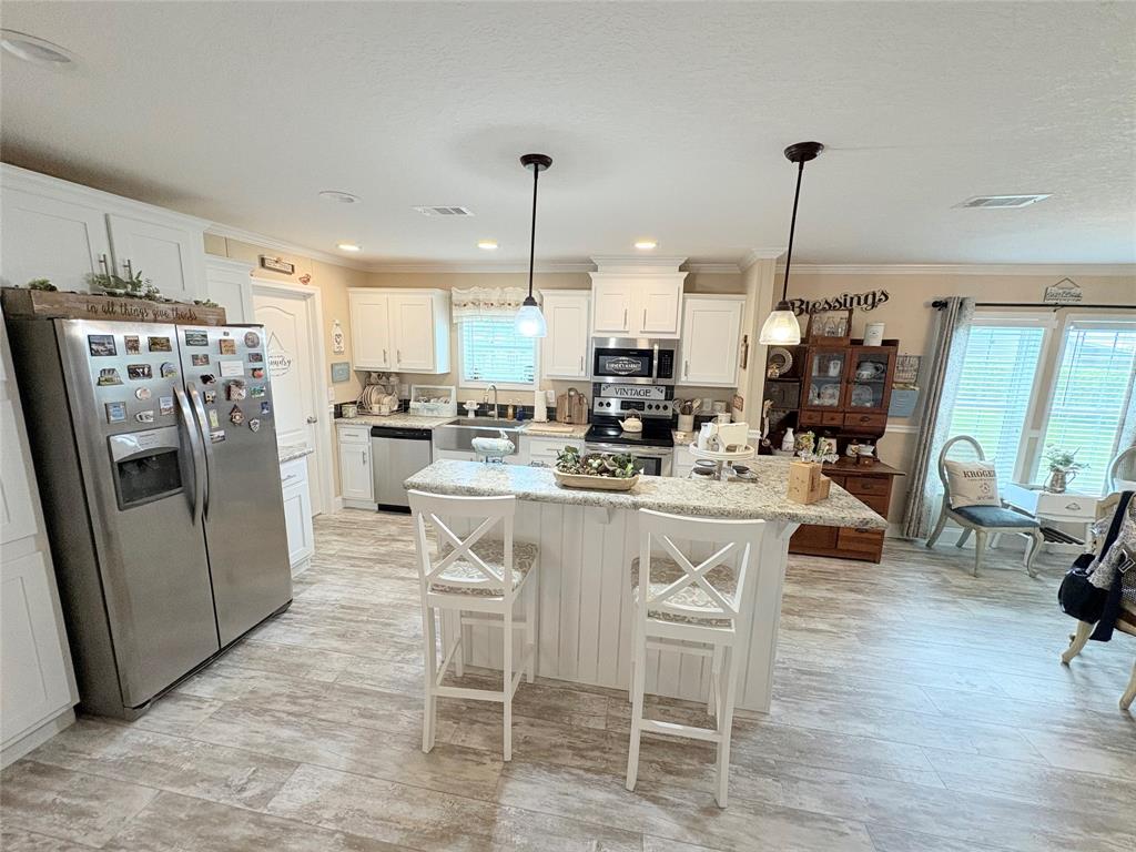4331 Southwest 10th Way Okeechobee, FL 34974 - Photo 3 of 49 a kitchen with stainless steel appliances kitchen island granite countertop a refrigerator a stove a dining table and chairs with wooden floor