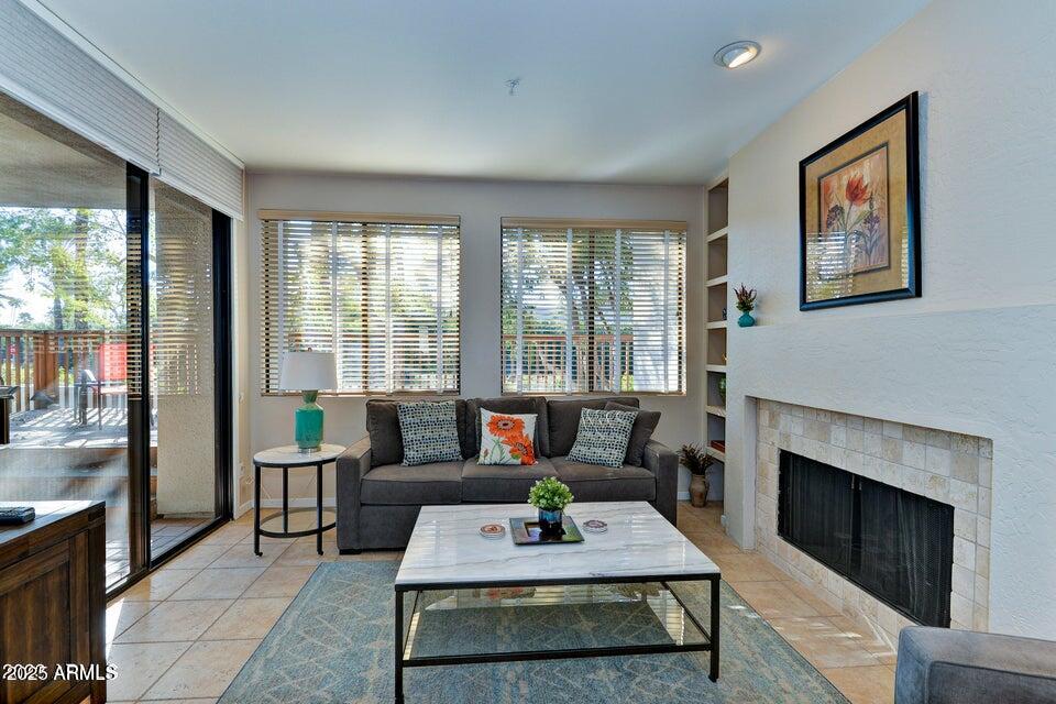 7700 East Gainey Ranch Road, Unit 104 Scottsdale, AZ 85258 - Photo 2 of 14 a living room with furniture a large window and a fireplace