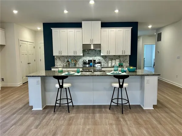 a kitchen with stainless steel appliances a table chairs refrigerator microwave and cabinets