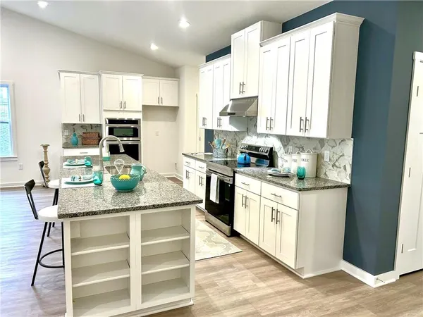 a kitchen with stainless steel appliances kitchen island granite countertop a stove a sink dishwasher and a refrigerator with wooden floor