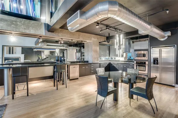 a dining room with stainless steel appliances kitchen island granite countertop a table chairs and wooden floor