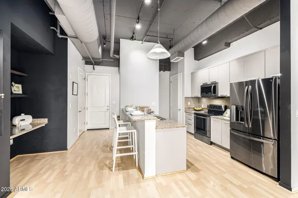 a kitchen with stainless steel appliances kitchen island granite countertop a refrigerator a stove top oven a sink and dishwasher