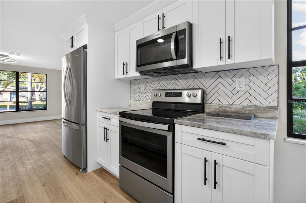 5612 Mallow Street New Port Richey, FL 34652 - Photo 12 of 43 a kitchen with stainless steel appliances granite countertop a stove microwave and refrigerator