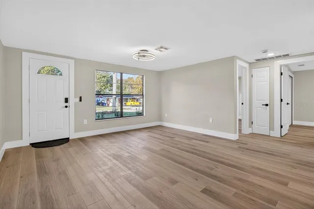 a bedroom with a bed and a lamp on dresser with a window