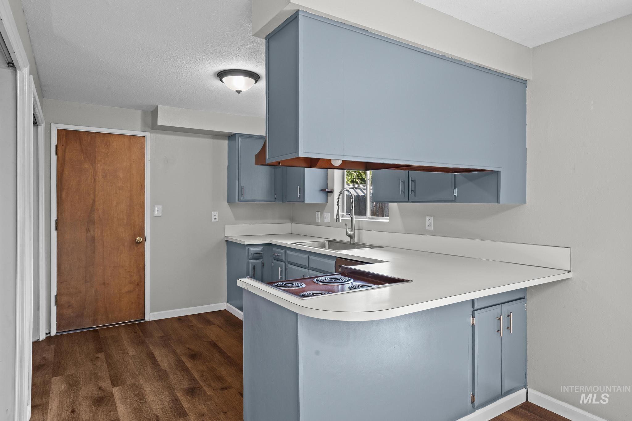 2037 South Curtis Road Boise, ID 83705 - Photo 13 of 32 Kitchen featuring wood-finish flooring, blue cabinetry, white countertops, and a built-in electric stovetop