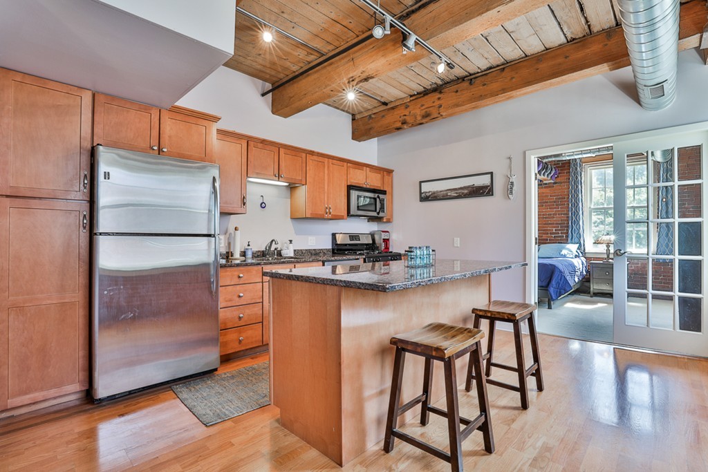 25 Cedar Street, Unit 4 Amesbury, MA 01913 - Photo 7 of 20 a kitchen with stainless steel appliances granite countertop a stove top oven a refrigerator a dining table and chairs with wooden floor