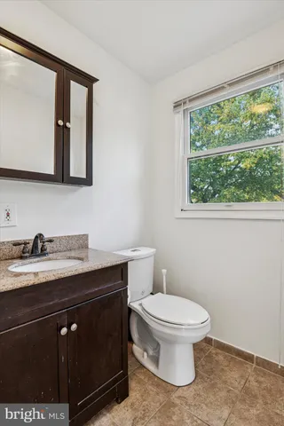 a bathroom with a granite countertop toilet sink and mirror