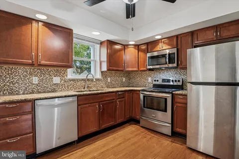 a kitchen with stainless steel appliances granite countertop a refrigerator a stove a sink dishwasher and microwave with wooden floor