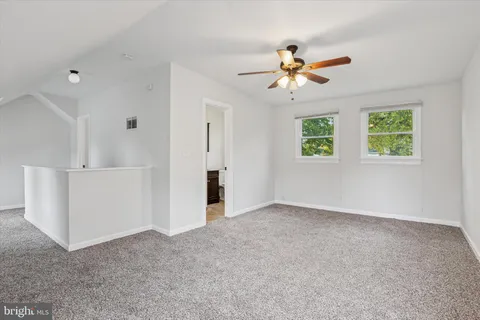 a view of an empty room with window and a ceiling fan