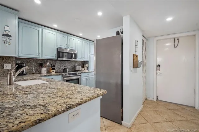 a kitchen with kitchen island granite countertop a refrigerator a sink a stove a microwave and island