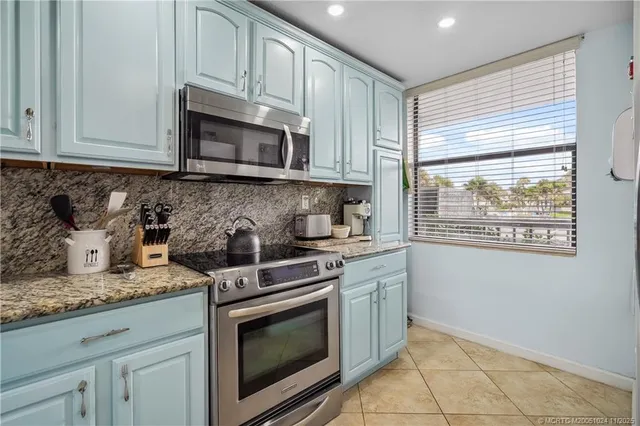 a kitchen with granite countertop white cabinets stainless steel appliances and a sink