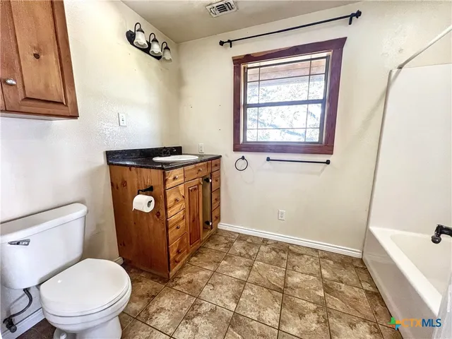 a bathroom with a granite countertop toilet a sink and a bathtub