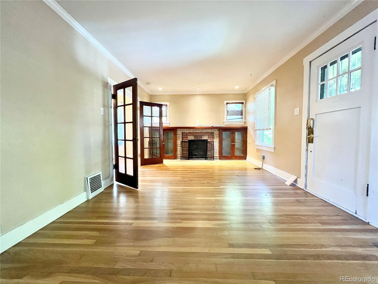 1146 Jackson Street Denver, CO 80206 - Photo 3 of 11 a view of an empty room with wooden floor and a window