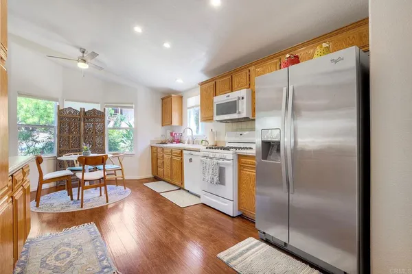 a kitchen with stainless steel appliances a refrigerator a stove dining table and chairs