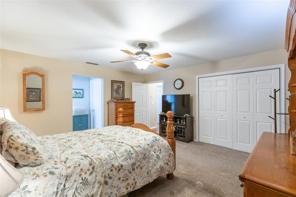 1603 Derrick Drive Haskell, TX 79521 - Photo 17 of 37 a bedroom with a large bed a flat tv screen and a chandelier