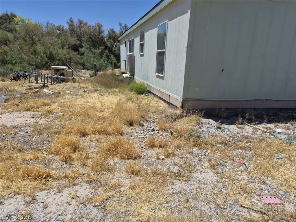2271 Tough Boy Road Pahrump, NV 89060 - Photo 4 of 12 A well-maintained single-story dwelling with ample yard space, framed by natural greenery under an expansive sky.