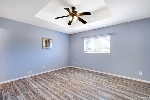 a view of empty room with wooden floor and fan