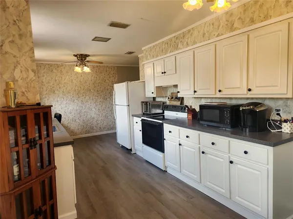 a kitchen with stainless steel appliances granite countertop a refrigerator a stove and white cabinets with wooden floor