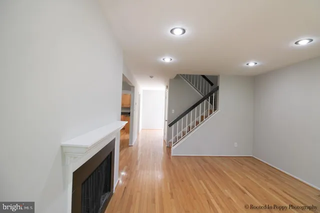 an empty room with wooden floor fireplace and windows