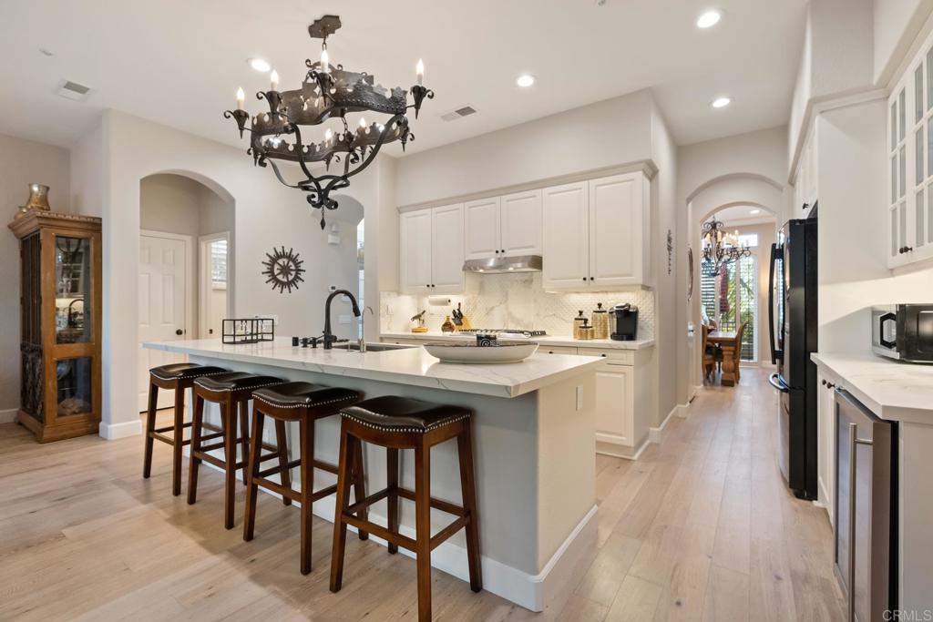 2721 MacKinnon Ranch Road Cardiff-by-the-Sea, CA 92007 - Photo 5 of 38 a kitchen with stainless steel appliances kitchen island granite countertop a table chairs in it and wooden floors