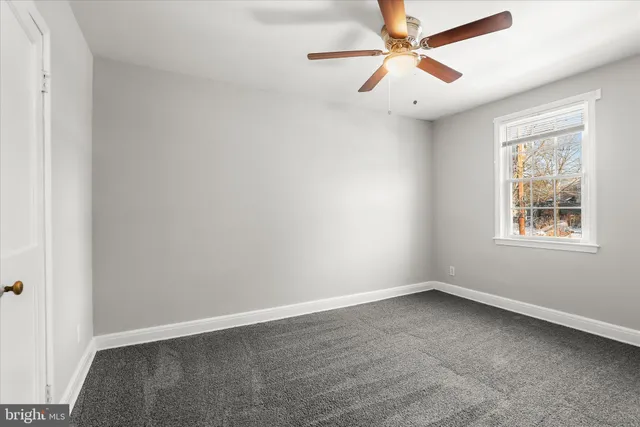 an empty room with a window and a fan