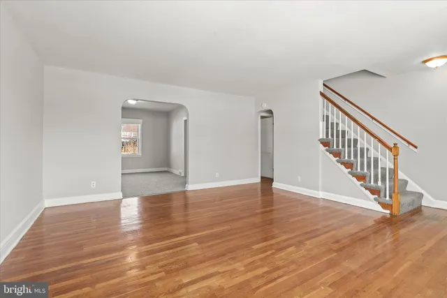 a view of an empty room with wooden floor and a potted plant