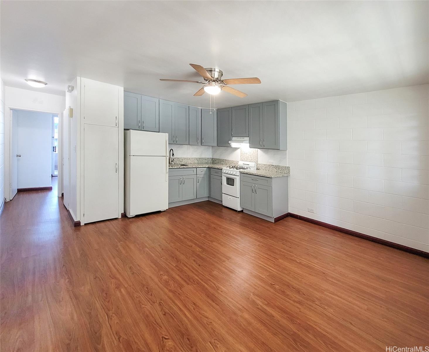 1555 Pensacola Street, Unit 302 Honolulu, HI 96822 - Photo 1 of 11 a view of a kitchen with wooden floor and a refrigerator