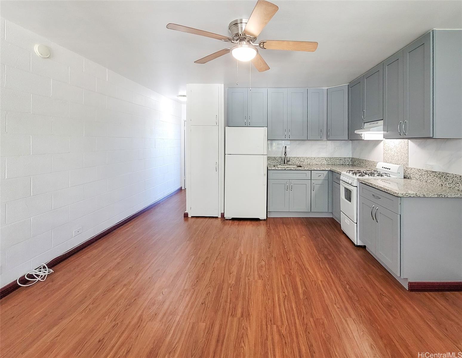 1555 Pensacola Street, Unit 302 Honolulu, HI 96822 - Photo 2 of 11 a kitchen with wooden floors and white cabinets