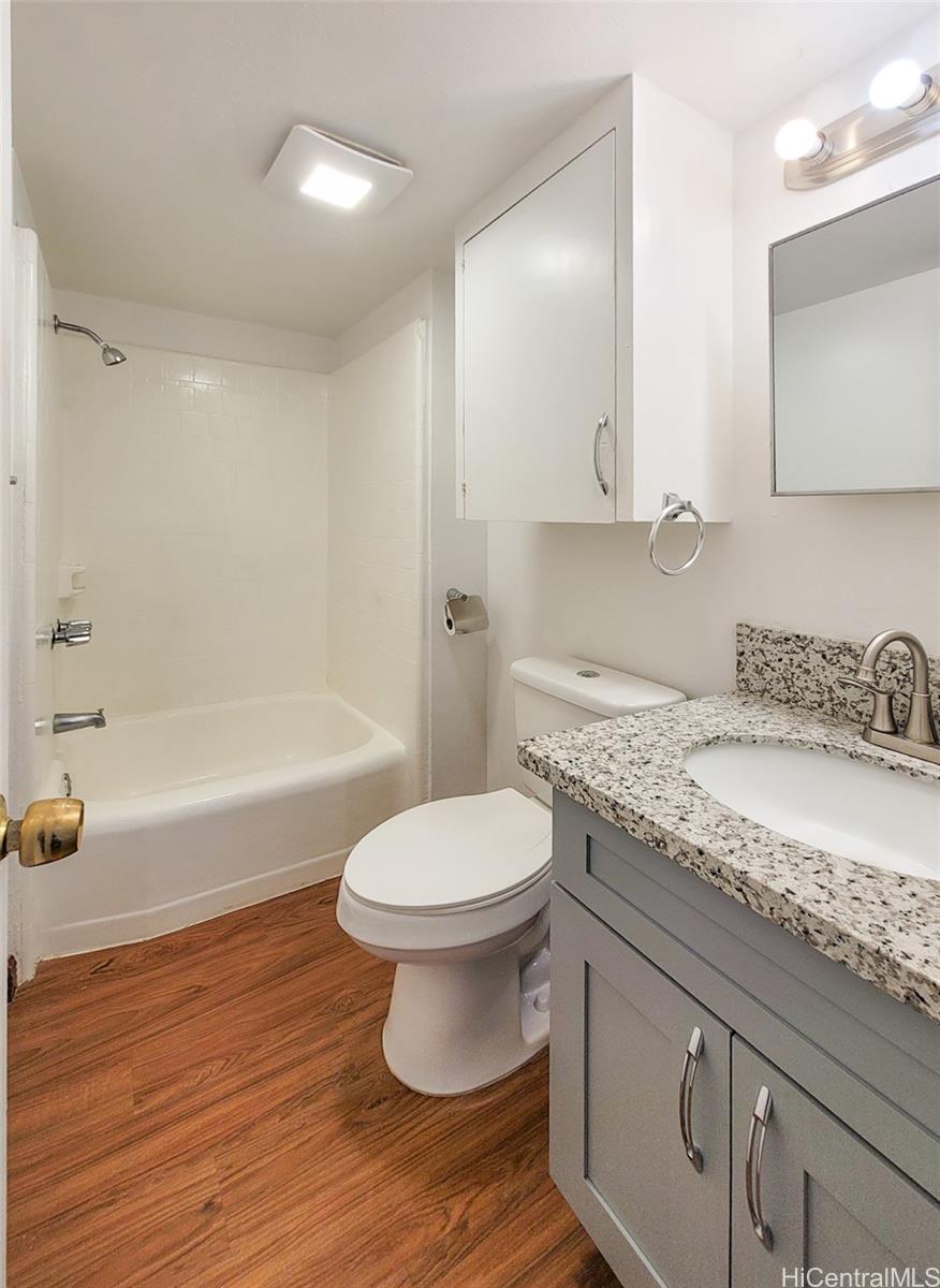 1555 Pensacola Street, Unit 302 Honolulu, HI 96822 - Photo 4 of 11 a bathroom with a granite countertop toilet a sink and bathtub