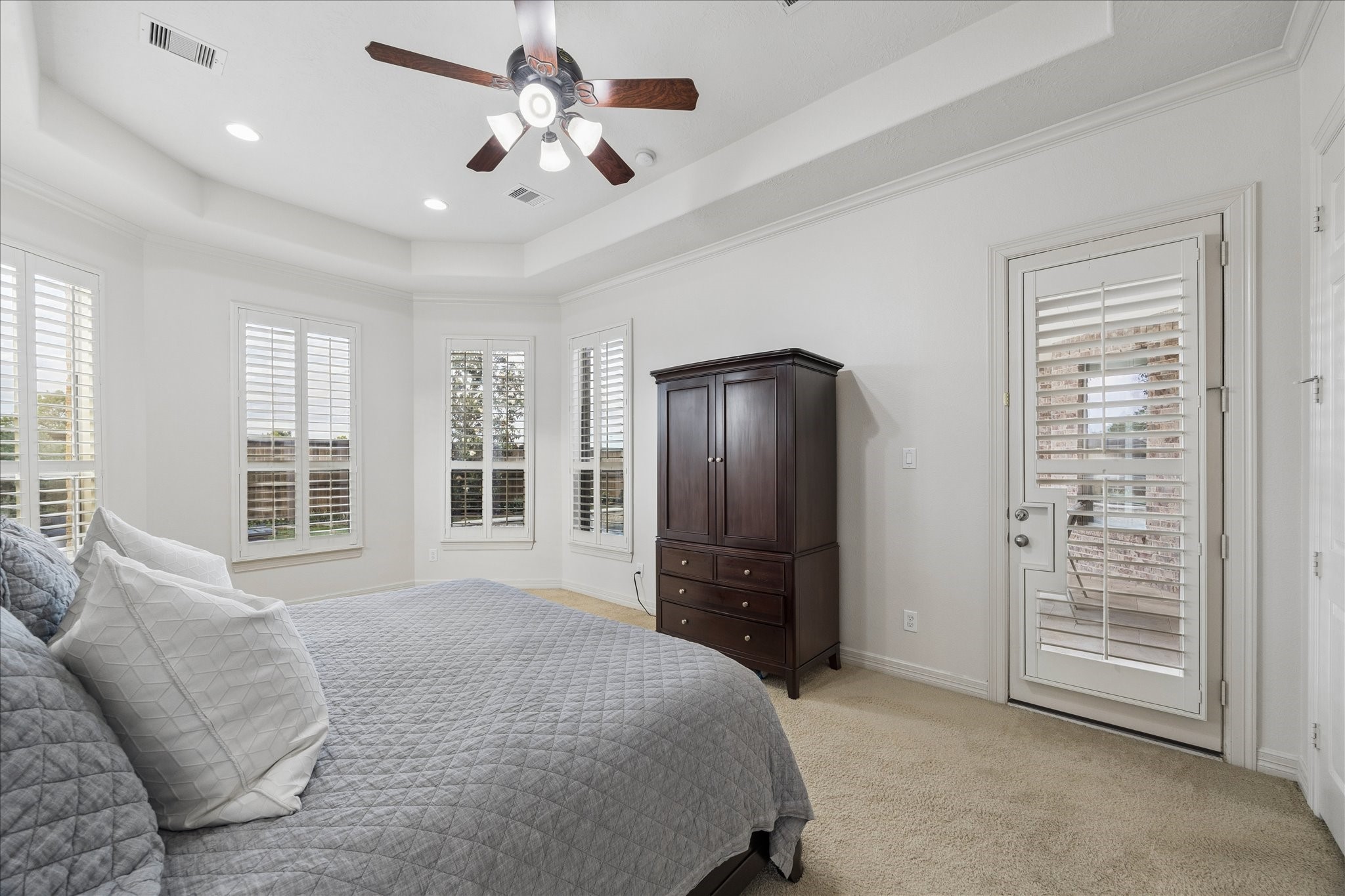 The primary suite features a seating cove overlooking the backyard and door leading directly to the patio and pool.