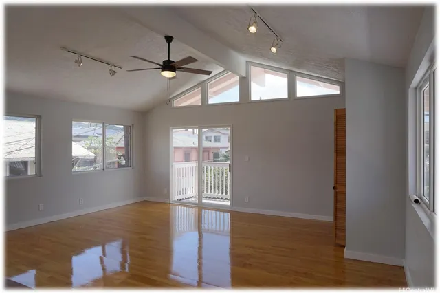a view of an empty room with wooden floor and a window
