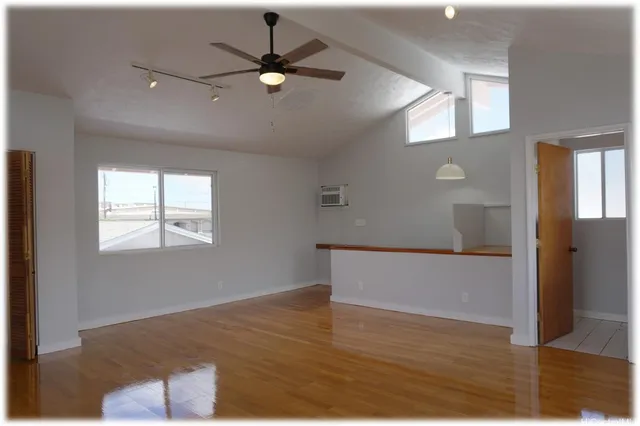a view of an empty room with wooden floor and a window