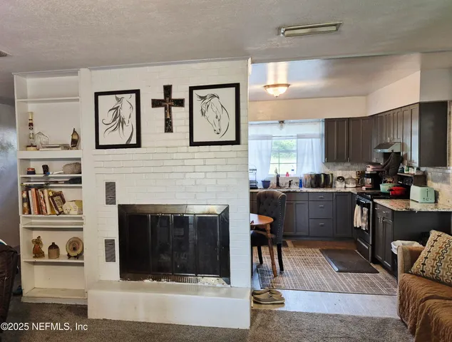 a living room with stainless steel appliances furniture a fireplace and a window