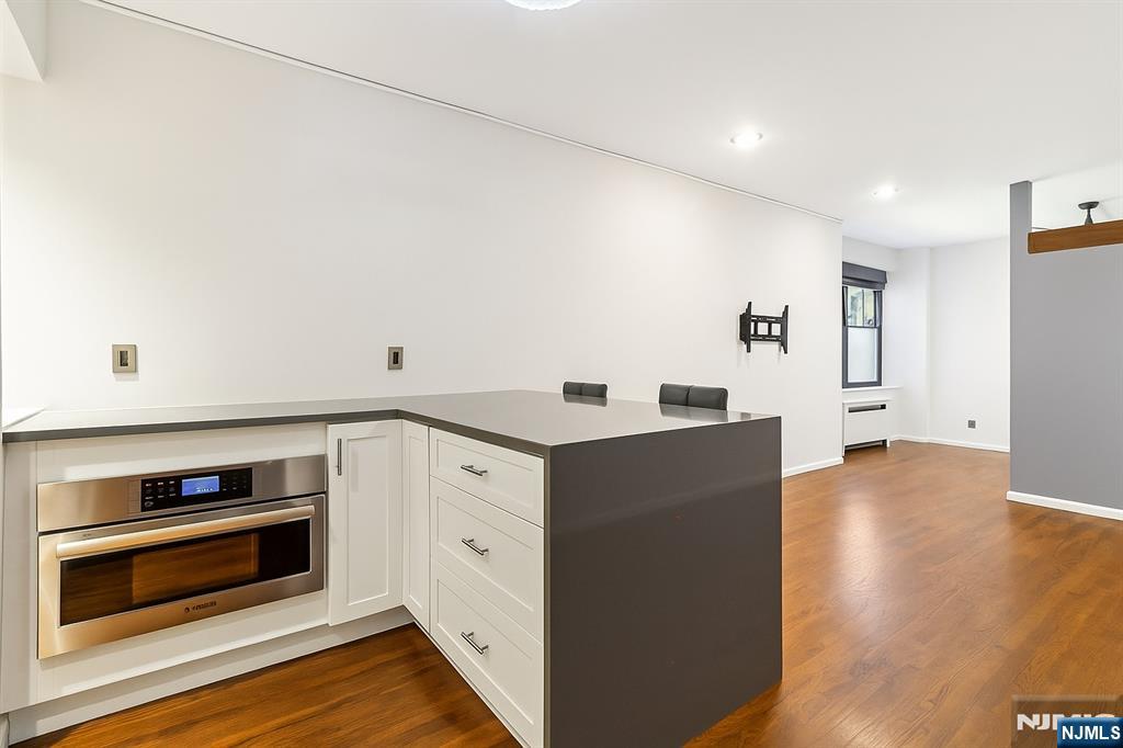 3050 Edwin Avenue, Unit 2D Fort Lee, NJ 07024 - Photo 12 of 21 a kitchen with wooden floor and cabinets
