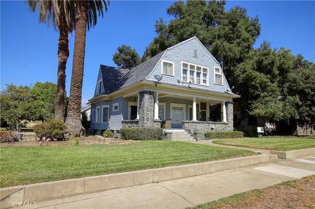a front view of a house with a garden and trees