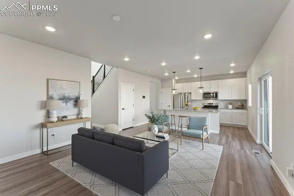 a kitchen with stainless steel appliances granite countertop white cabinets a refrigerator a stove a sink and dishwasher with wooden floor